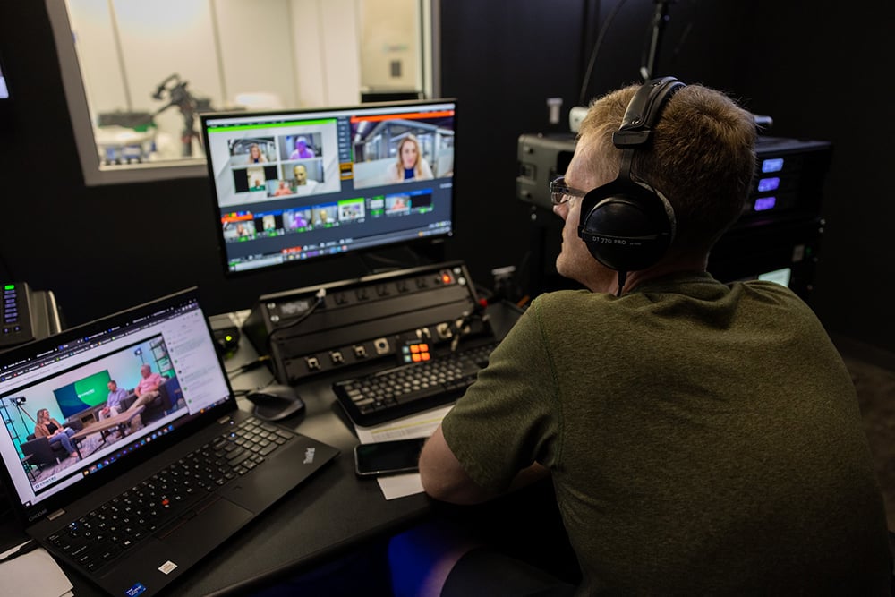 man looking at two desktop with headphones on